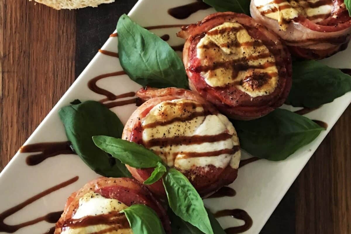 Grilled tomatoes on a white plate drizzled with a balsamic glaze.