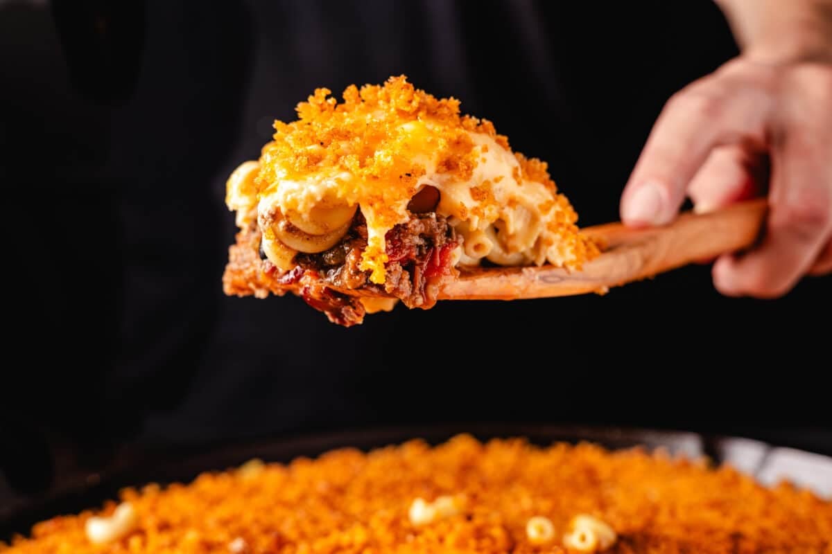 A wooden spatula holding up a scoop of chili mac.