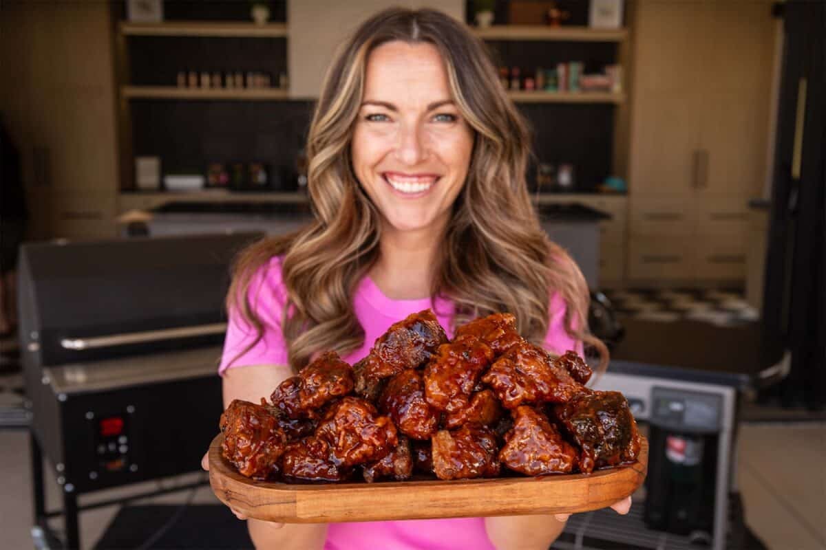 A shot of Susie holding a wooden platter of battered brisket burnt ends.