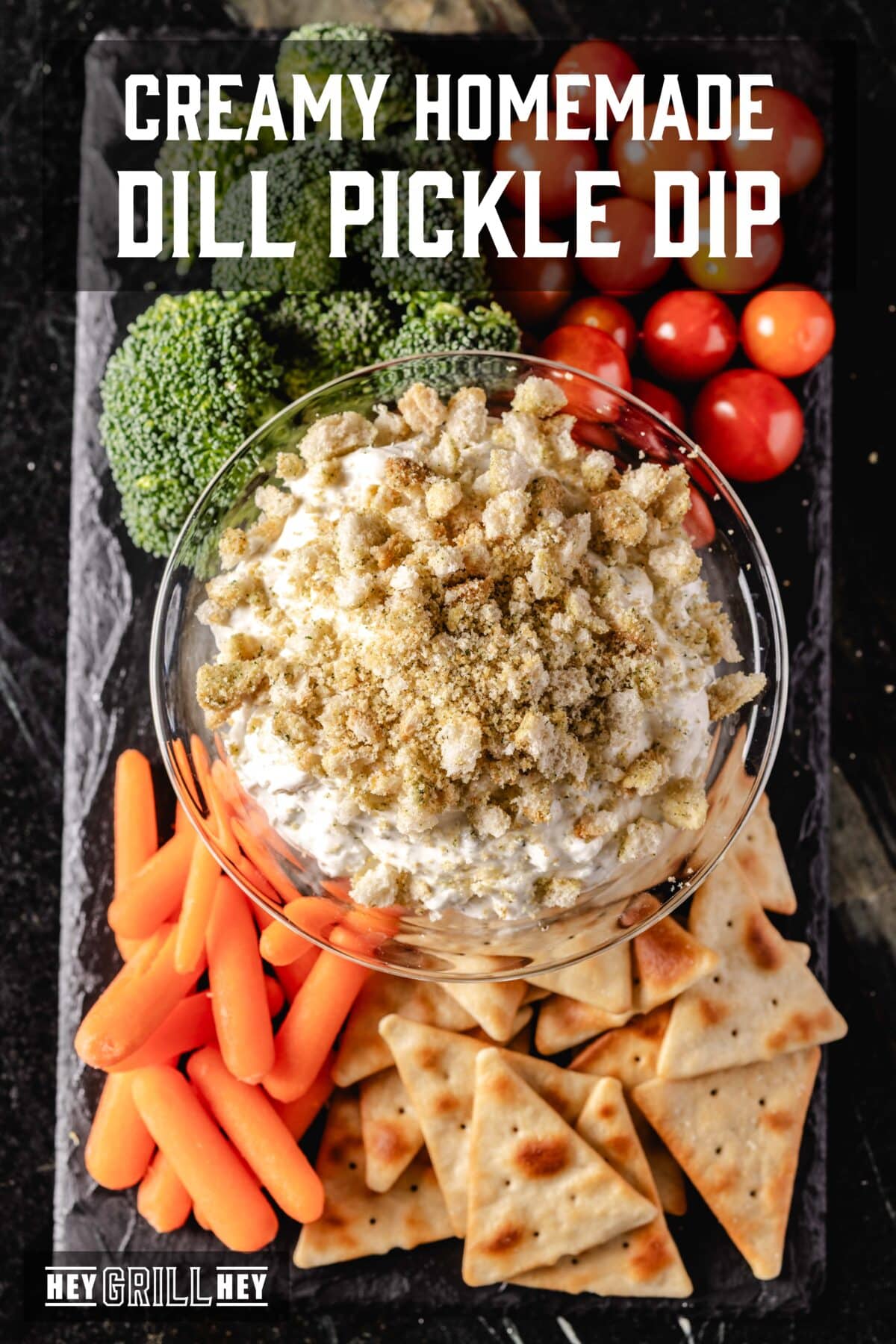 An overhead shot of a dip on a board lined with various veggies. The text overlay reads " Creamy Homemade Dill Pickle Dip" at the top, and "Hey Grill Hey" at the bottom.