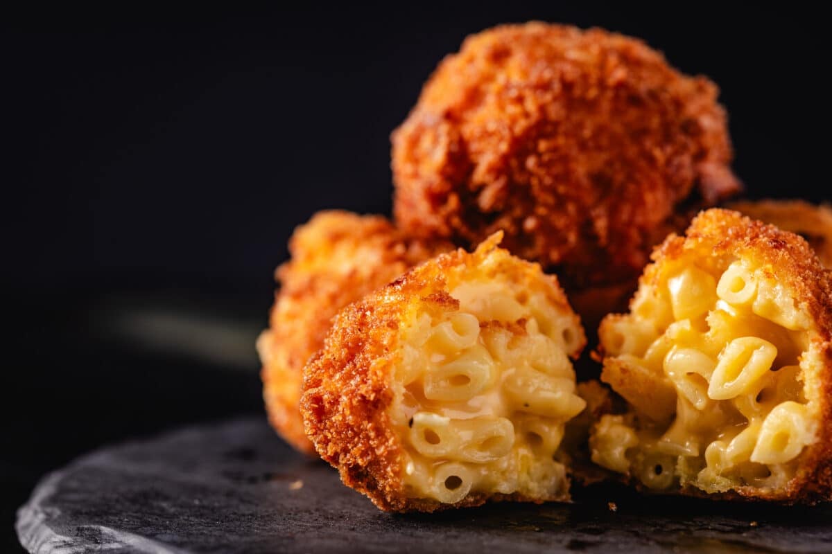 Mac and cheese bites stacked on a black plate.