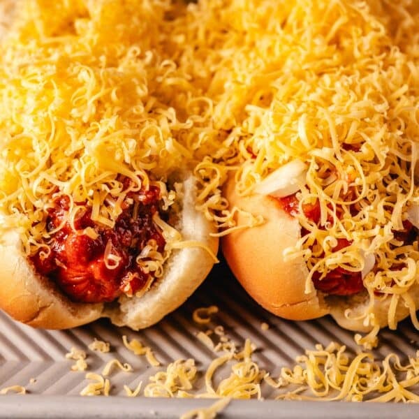 A closeup shot of two Skyline Coneys on a baking sheet covered in chili and shredded cheese.