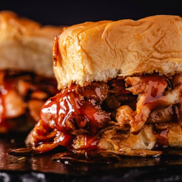 A closeup shot of a shredded chicken sandwich dripping with BBQ sauce.