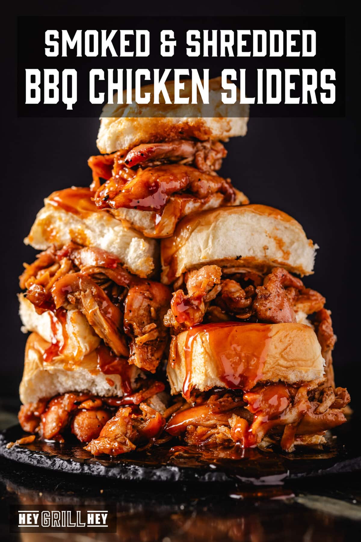 Chicken sliders stacked on a black plate. The Text overlay reads "Smoked & Shredded BBQ Chicken Sliders" at the top, and "Hey Grill Hey" at the bottom.