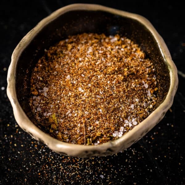 A bowl filled with a spice blend on a black background.