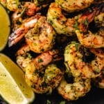 Grilled shrimp next to lime wedges.