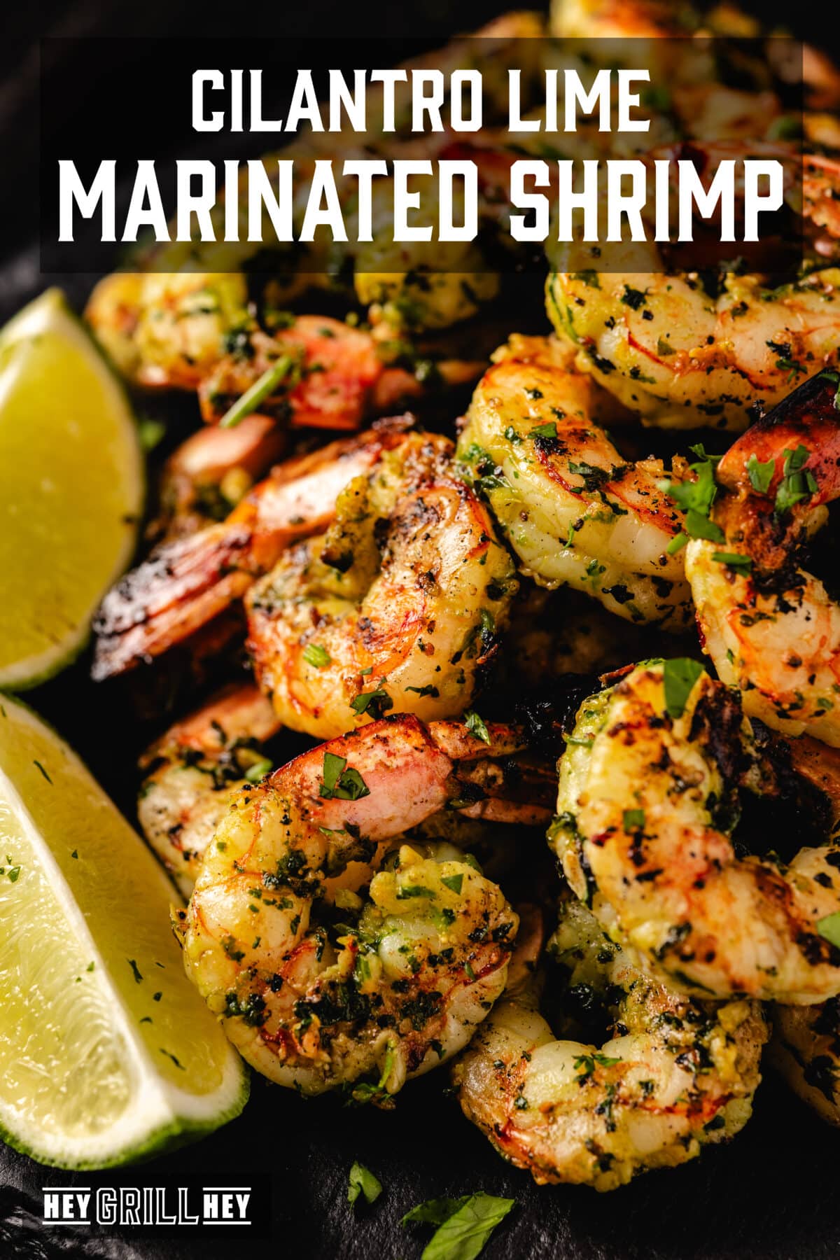 Grilled shrimp piled next to lime wedges on a black plate. The text overlay reads "Cilantro Lime Marinated Shrimp" at the top, and "Hey Grill Hey" at the bottom.