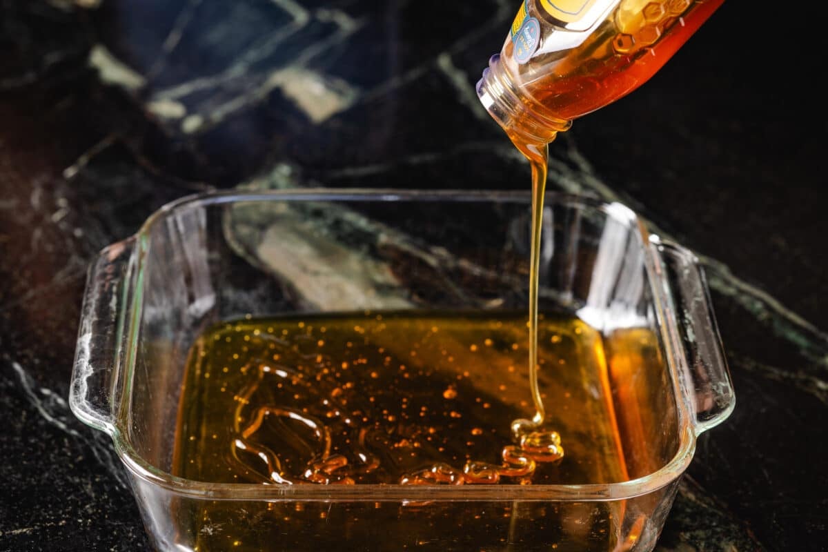 Honey is poured by a bottle in a pan.