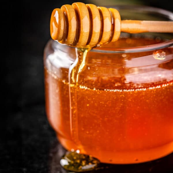A honeycomb resting on top of a jar of smoked honey.