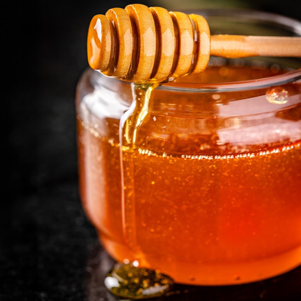 A honeycomb resting on top of a jar of smoked honey.