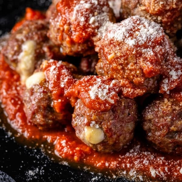 Meatballs dusted with Parmesan cheese on a bed of marinara sauce.