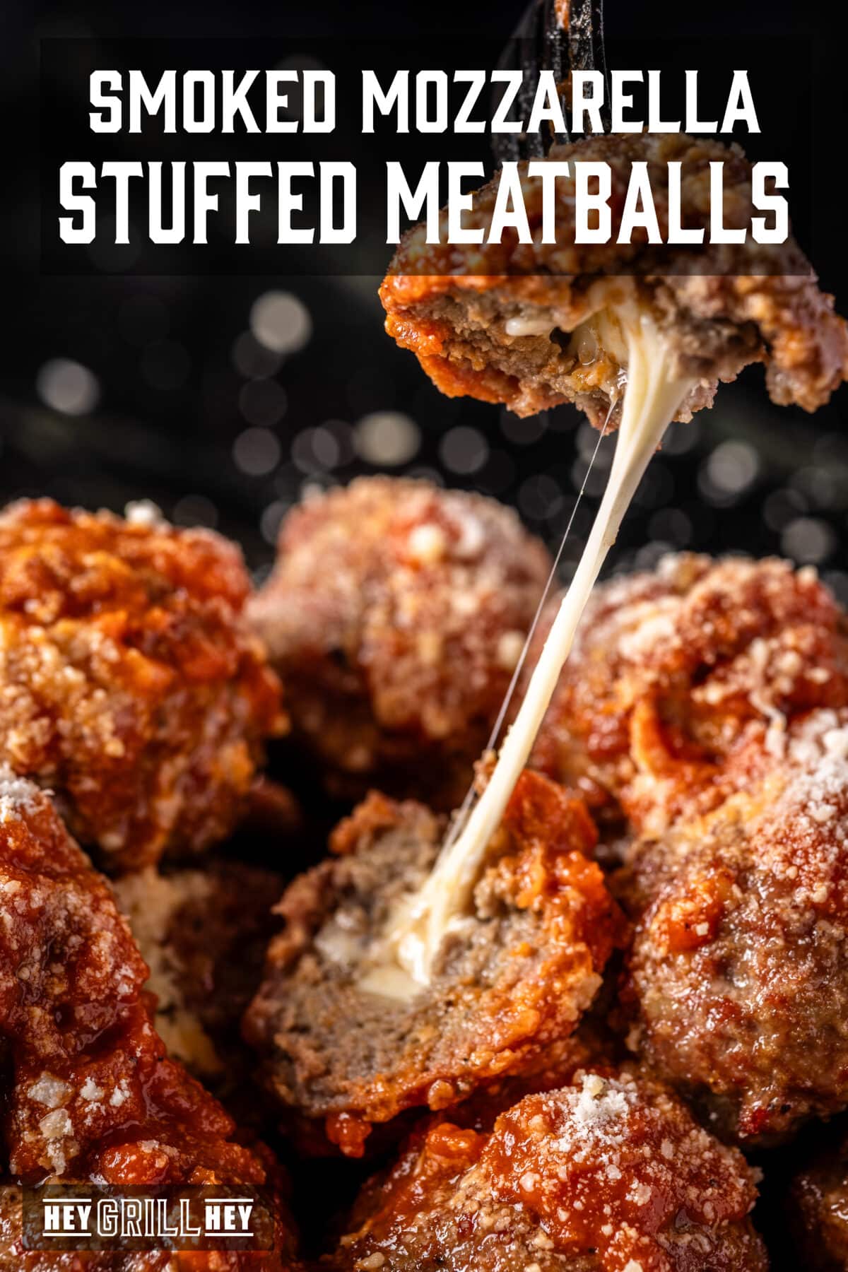 A stuffed meatball being pulled apart, revealing melted cheese inside. The text overlay reads "Smoked Mozzarella Stuffed Meatballs" at the top, and "Hey Grill Hey" at the bottom.