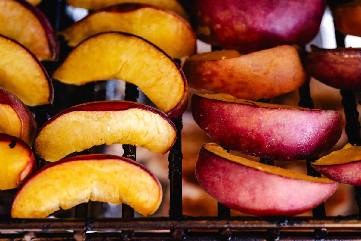 Peach slices on the grates of a smoker.