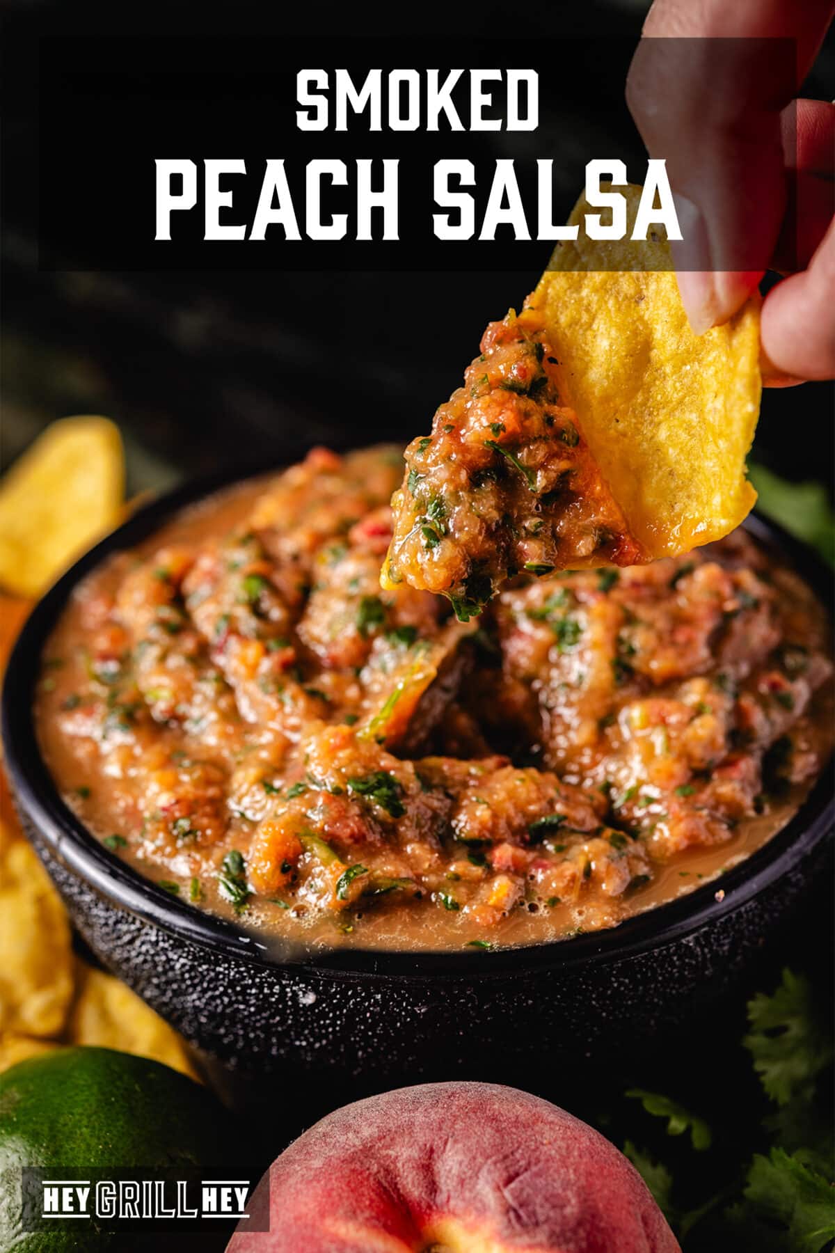 A hand dipping a chip into a bowl of salsa. The text overlay reads "Smoked Peach Salsa" at the top, and "Hey Grill Hey" at the bottom.