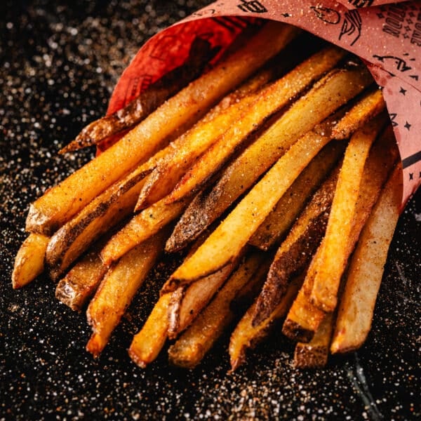 A batch of French fries wrapped in peach butcher paper.