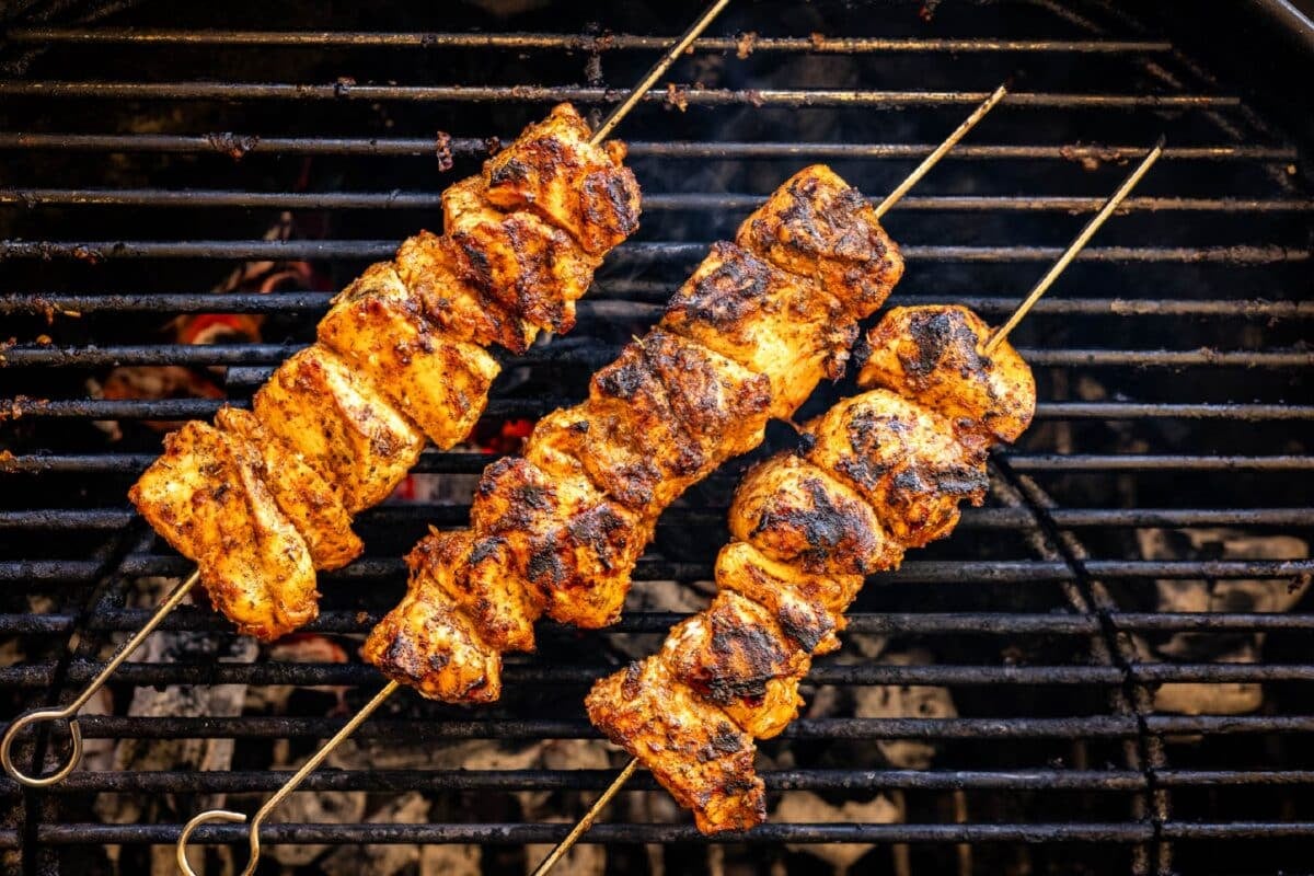 Skewered poultry on the grates of a grill.