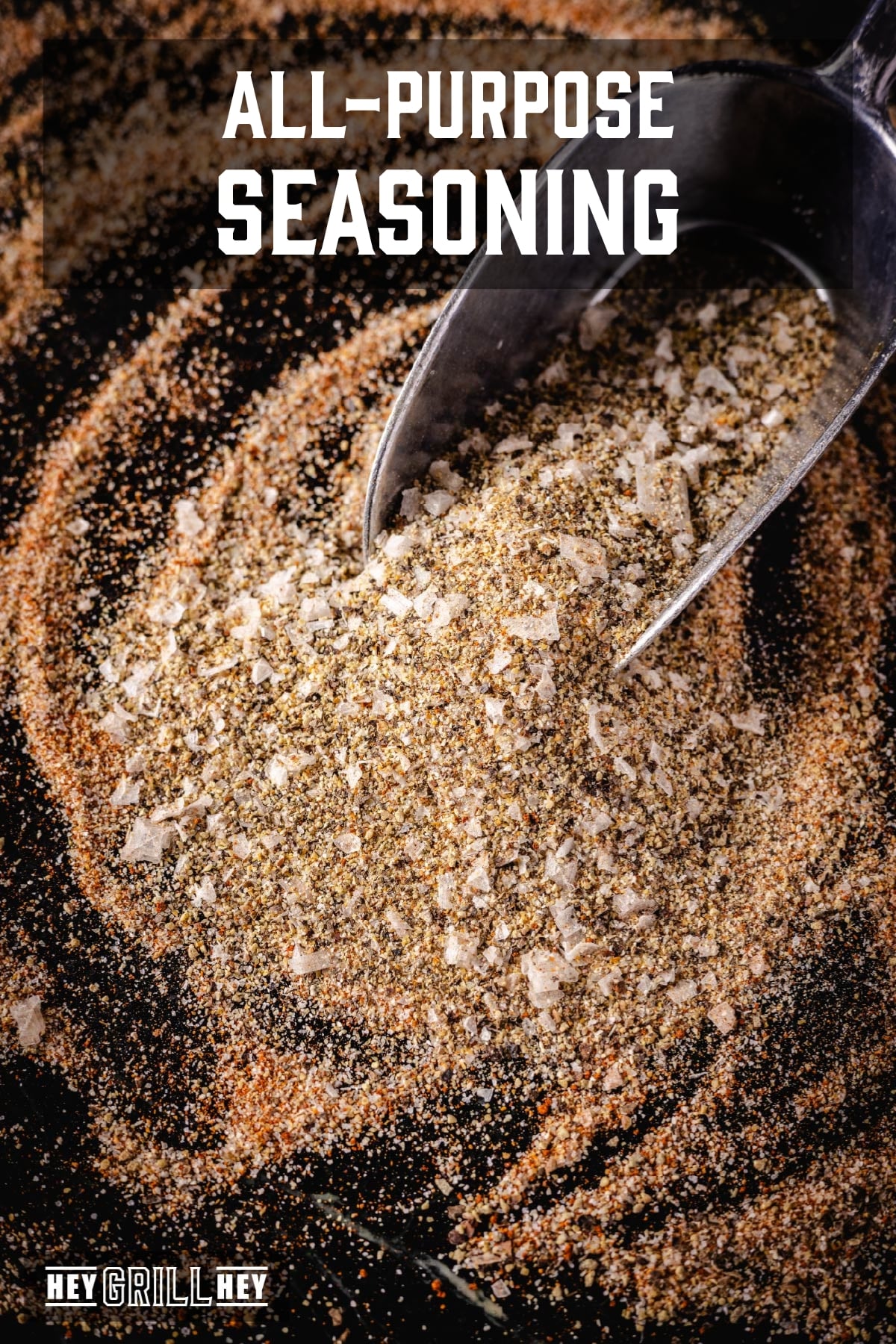 A metal scoop in a pile of seasoning. The text overlay reads "All-Purpose Seasoning" at the top, and "Hey Grill Hey" at the bottom.