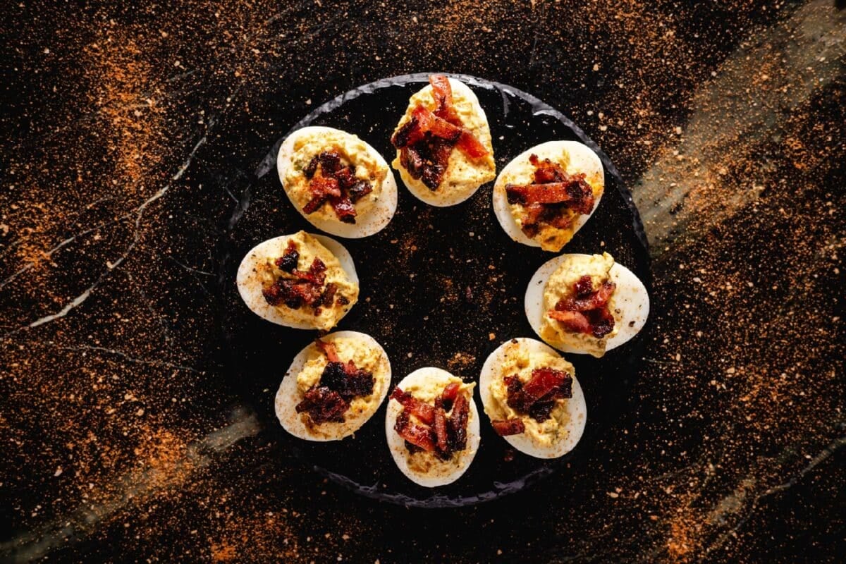 A round, black plate with deviled eggs in a circle.