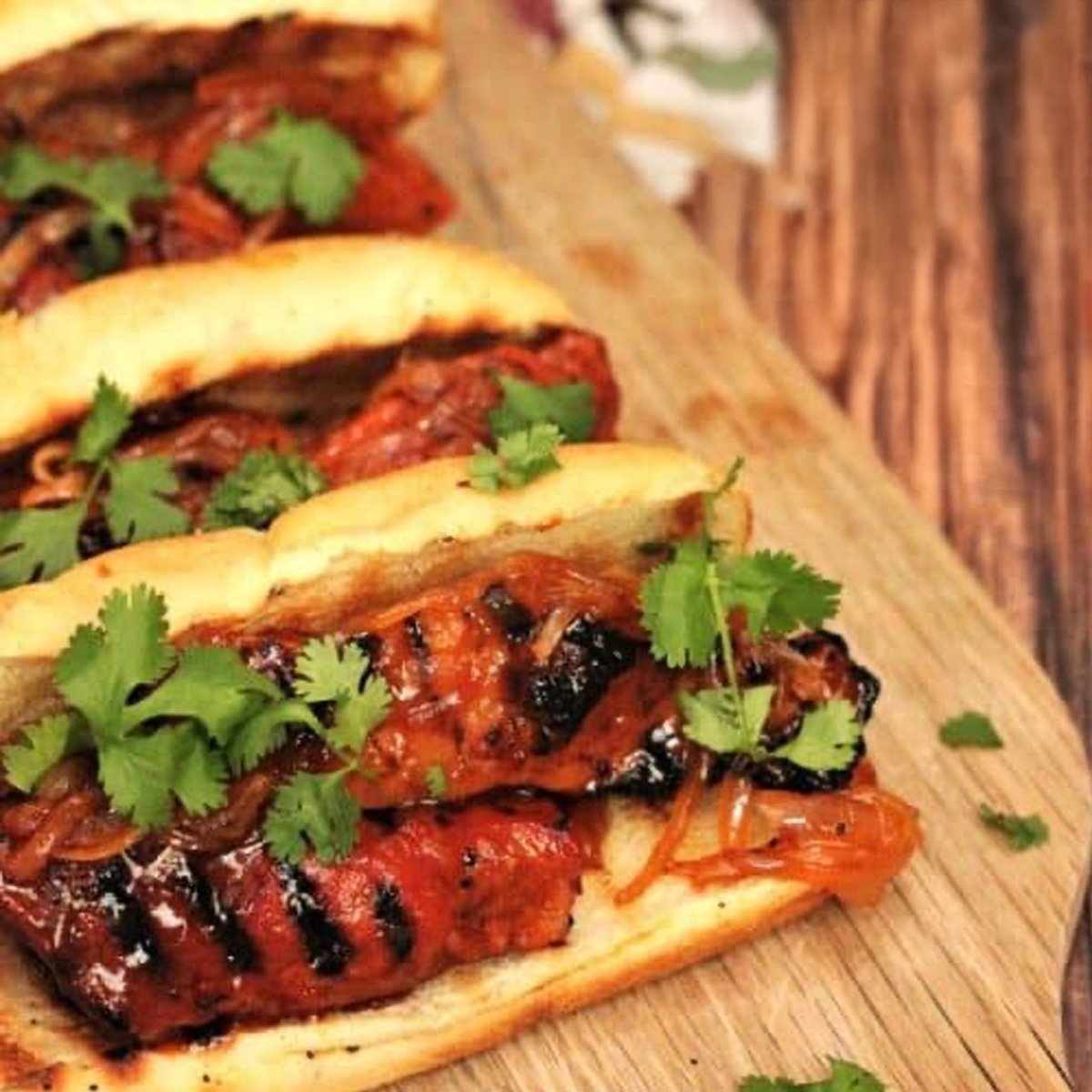 Three rib sandwiches on a wooden cutting board.