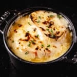 A closeup shot of a cast iron bowl filled with French onion soup.