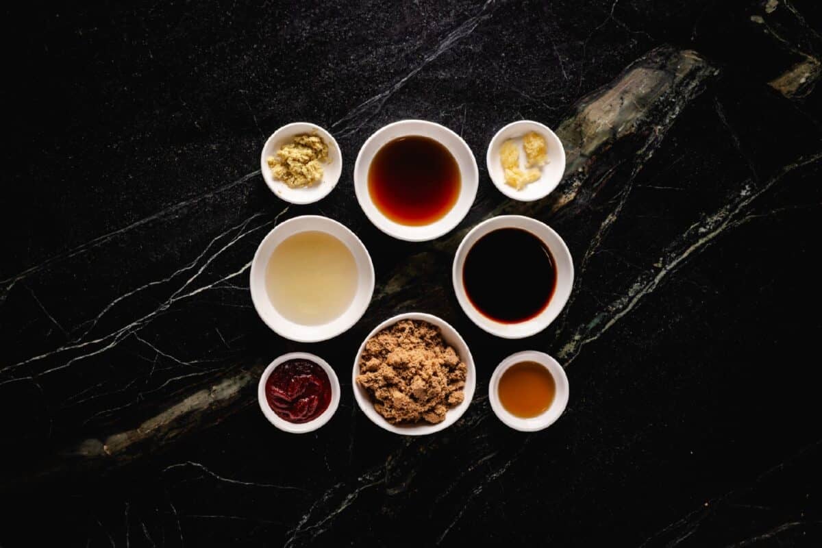 Eight bowls of liquid and granulated ingredients sitting on a marble countertop.
