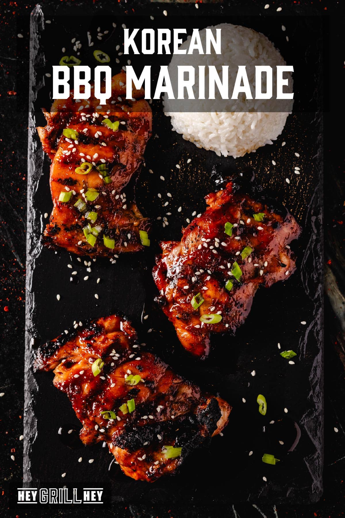 Smoked chicken thighs topped with sliced green onions and sesame seeds, and a scoop of rice on a black platter. The text overlay reads "Korean BBQ Marinade" at the top, and "Hey Grill Hey" at the bottom.