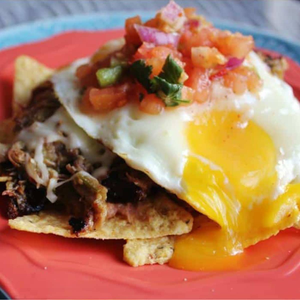A red plate topped with a BBQ huevos rancheros breakfast recipe.