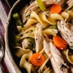 A close up shot of a bowl filled with chicken noodle soup.